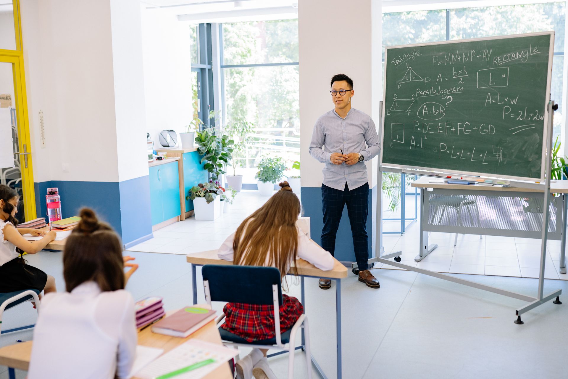 Joven docente de inglés imparte clase con confianza en un aula internacional luminosa en España